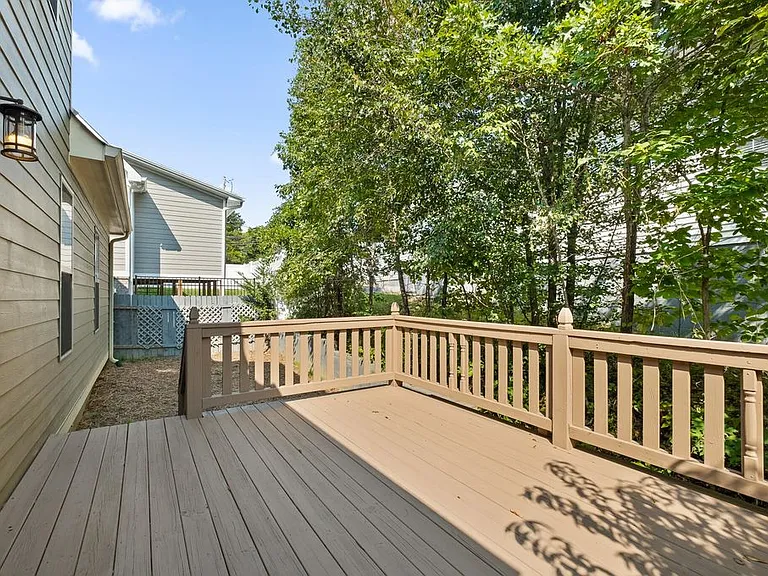 Back deck off tall shade trees and steps leading to yard area.