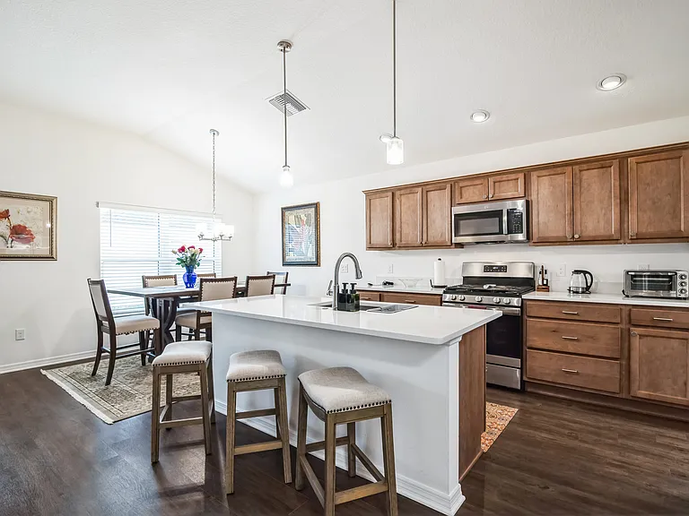 The Kitchen Area has a Large Island with Sink and Bar Sitting Area for Three.
