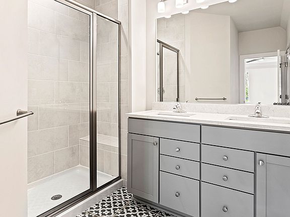 Owner s bathroom with gray, dual sink vanity and walk-in, tiled shower in a DRB Homes Latitude home.