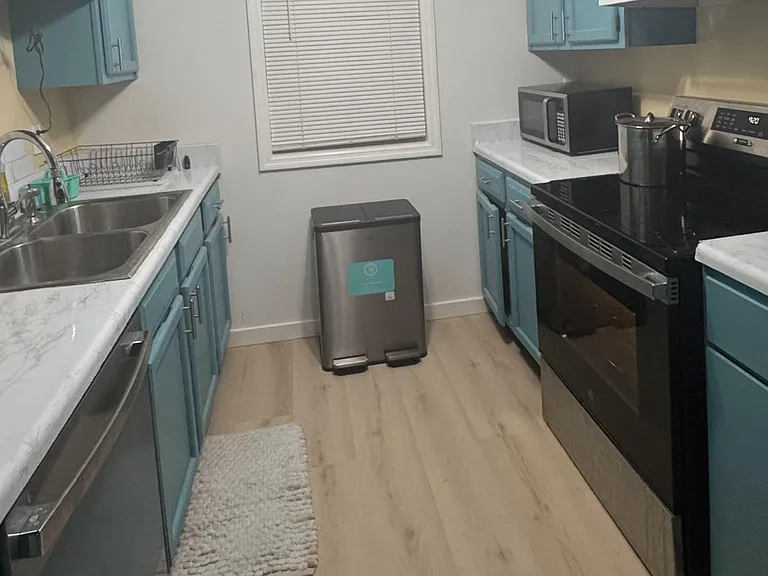 Efficient galley kitchen with ample cabinet storage, generous counters, double-basin sink, and full-size range.