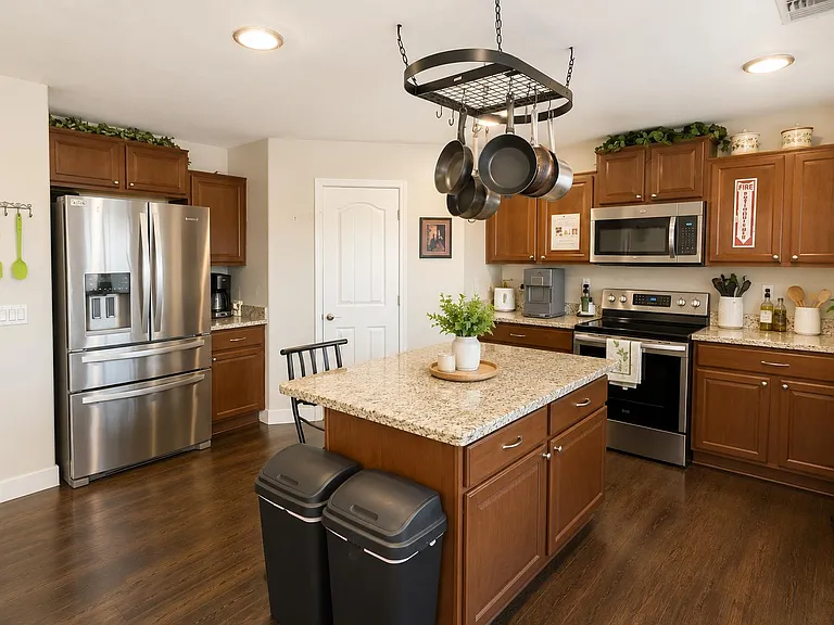 Spacious kitchen with granite island, ample cabinetry, and stainless steel appliances plus a handy hanging pot rack.