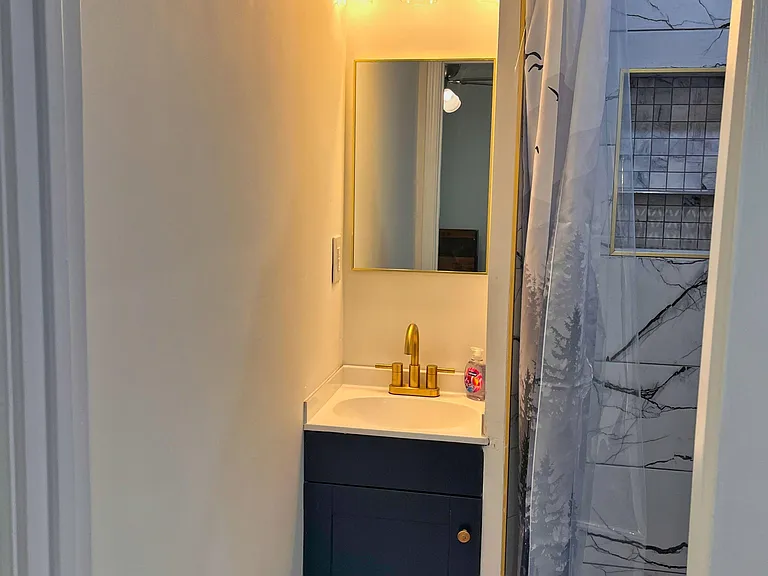 Updated bathroom with a vanity sink, framed mirror, and a tiled shower featuring a built-in niche for toiletries.