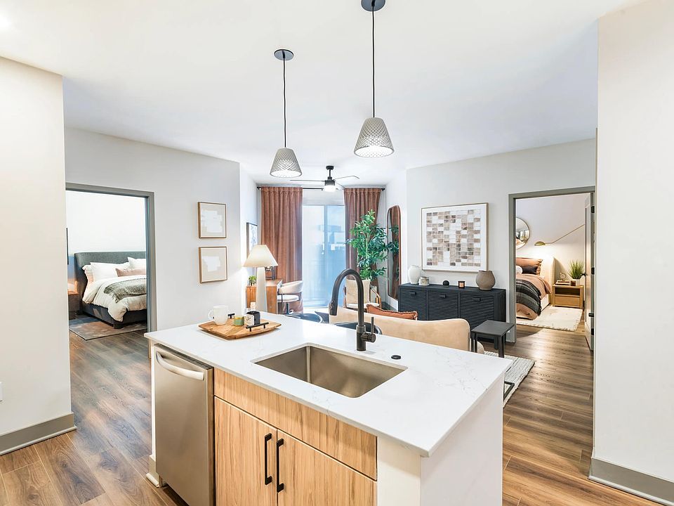 Open-concept kitchen and living area with access to dual bedrooms, warm finishes, and wood-style flooring throughout.