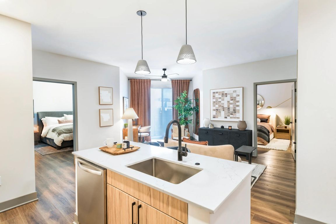 Open-concept kitchen and living area with access to dual bedrooms, warm finishes, and wood-style flooring throughout.