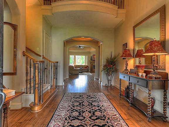  The entry of this prestigious custom built home warmly welcomes guests with beautiful arched wrought iron double doors and rich hardwood flooring! The iron staircase and second floor veranda beautifully accent this impressive reception area!