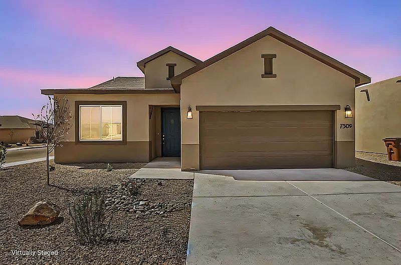 Single-story beige house with a two-car garage and a blue front door under a purple and pink sunset