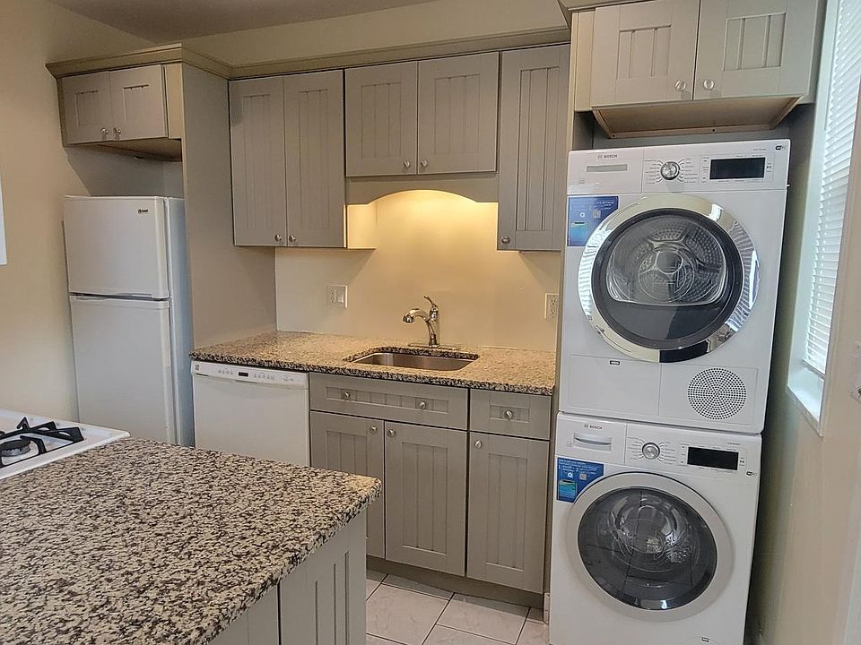 Kitchen with granite counters, gas stove, tile floor and Bosch washer and dryer.