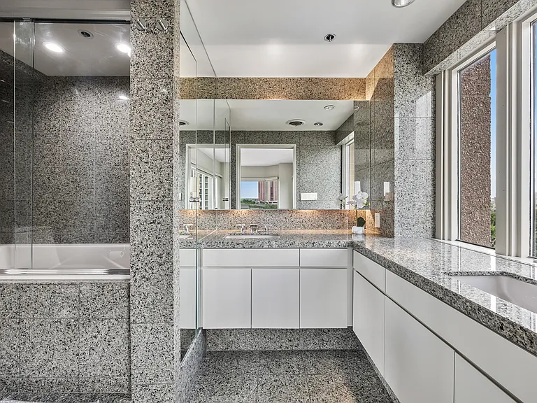 Light-filled primary bath with dual vanities, and stone-clad finishes.