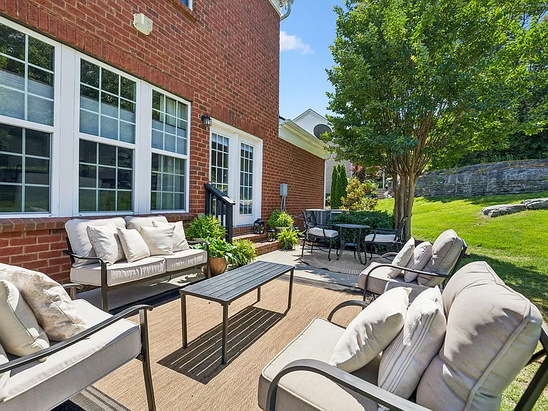 The walkout patio extends the home's living space outdoors, featuring multiple gathering areas that invite year-round enjoyment of the beautifully landscaped backyard.