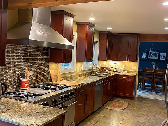 Gourmet kitchen fully stocked with flatware, plates, and cookware.