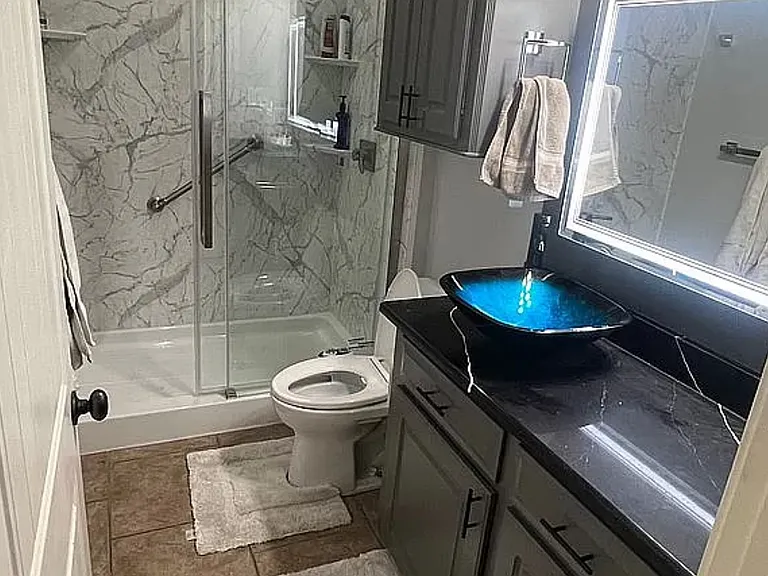 Modern guest bath with glass shower and quartz counter.