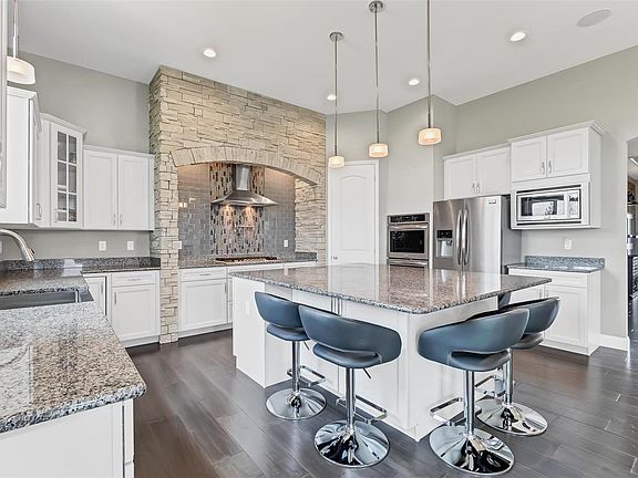 Huge Center Island, Double Ovens, Custom Finished Shelving in the walk in pantry, Stone Surround Range and Gas Stove with pot filler, Refrigerator included in sale, Apron Sink, Staggered Cabinets with Crown Molding, Soft Close Cabinets with Lazy Susan and pull drawers, Hardware, Glass accents, Recessed Lighting, Surround Sound and Subway Backsplash