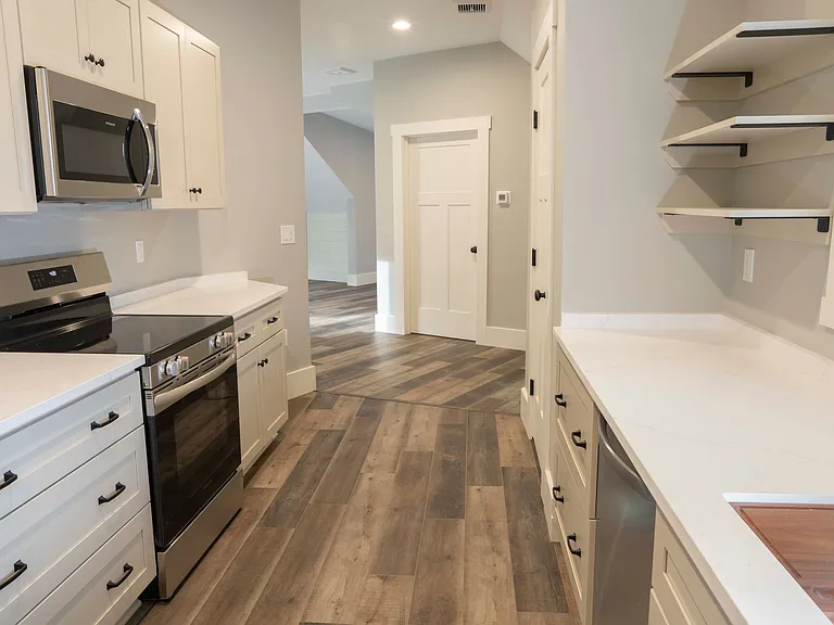Kitchen with brand-new stainless steel appliances and quartz countertops. Wood-like laminate floors throughout.