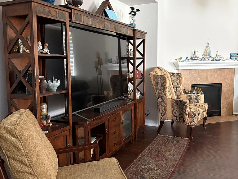 Living area with entertainment center, ample seating, and a fireplace focal point, offering space to relax and gather.