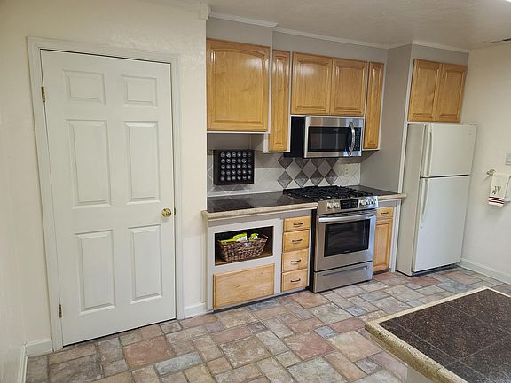 Newer range/oven & microwave. Custom cabinets include wicker snack basket, heavy pan drawer, spice rack (spices not included) roomy pantry, refrigerator, tile floors & backsplash, granite counters.