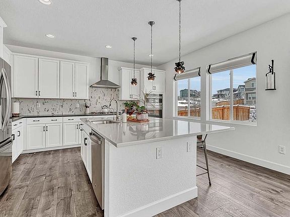 Chef's kitchen with oversized quartz island, pendant lighting, and gas range