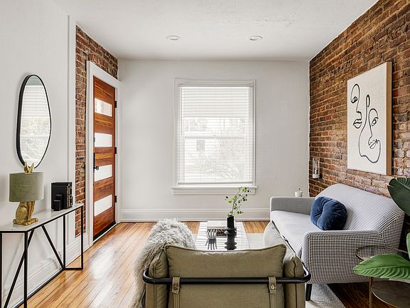 A harmonious blend of modern design and classic charm, this cozy living space features brick accent walls and a custom milled windowed door with natural light which creates an inviting ambiance.