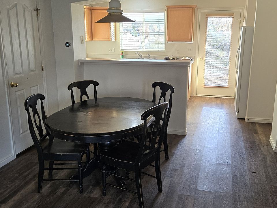 View of dining area towards fully fitted kitchen and yard beyond. Door is to understairs powder room. Door to garage is on right behind pillar.