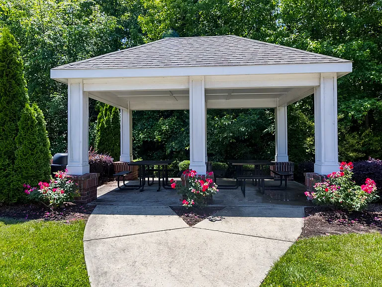 Charming community pavilion surrounded by vibrant landscaping and mature trees, perfect for social gatherings at Snowden Senior Apartments.