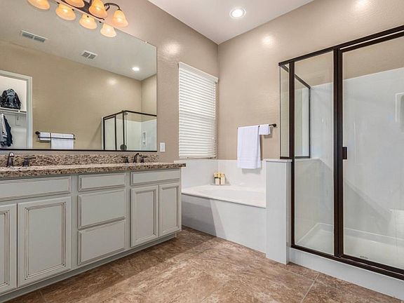 Master bath, separate WC, two sinks, separate bath and shower, and large walk in closet with small dresser.