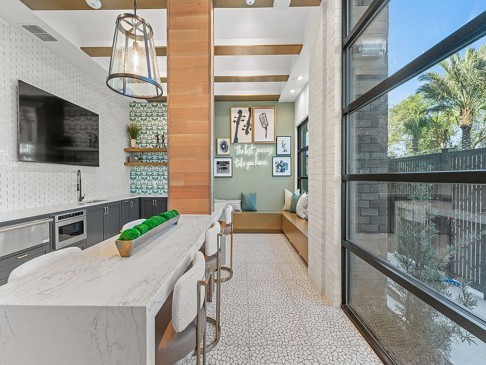 Chic modern kitchen with a stylish island, elegant lighting, and cozy seating area with a scenic view through large window.