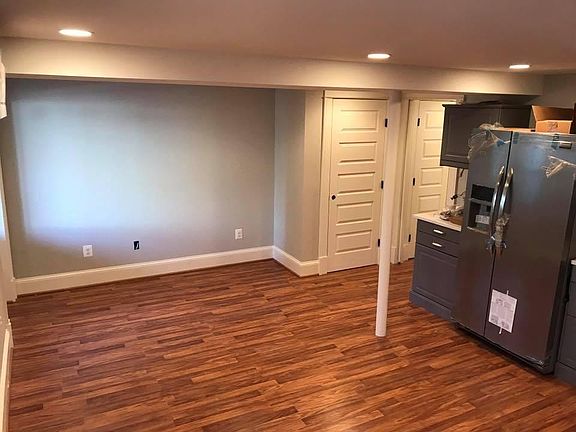 Living room space adjacent to the open kitchen; front door and ground-level entrance to the left