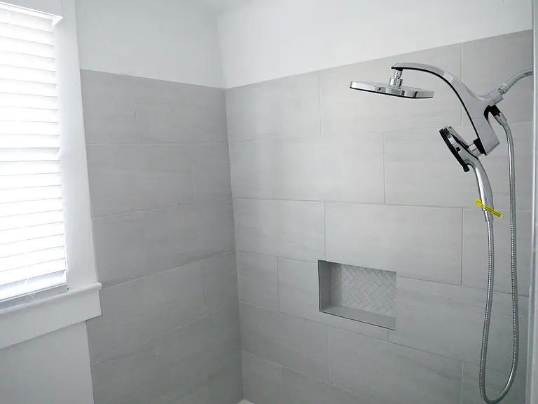 Fully renovated bathroom featuring modern tile, rainfall shower, and clean contemporary finishes