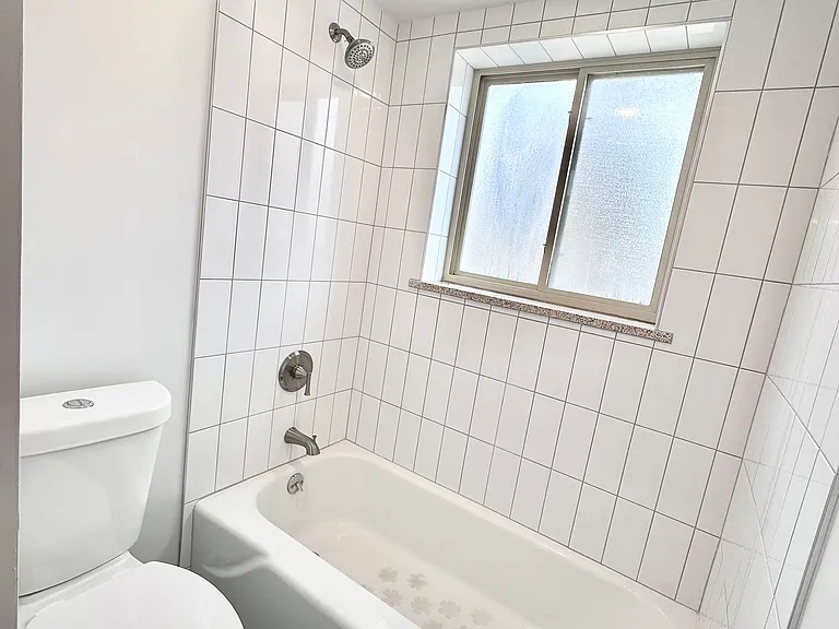 Bright, modern bathroom featuring sleek white tiles, a pristine bathtub, and contemporary fixtures. Bright, modern bathroom featuring sleek white tiles, a pristine bathtub, and contemporary fixtures.