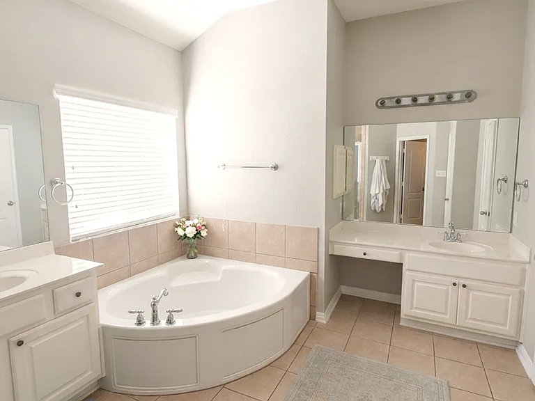 Primary bath with corner garden tub, dual vanities, and makeup vanity