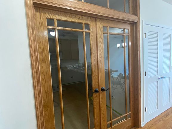 Den/office with closet and French doors which include privacy curtains.