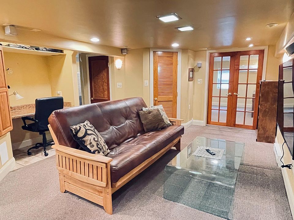 Fully furnished Living Area with leather futon sofa, wall mounted large flat-screen TV, bookshelf, built in desk, coffee table, large closet