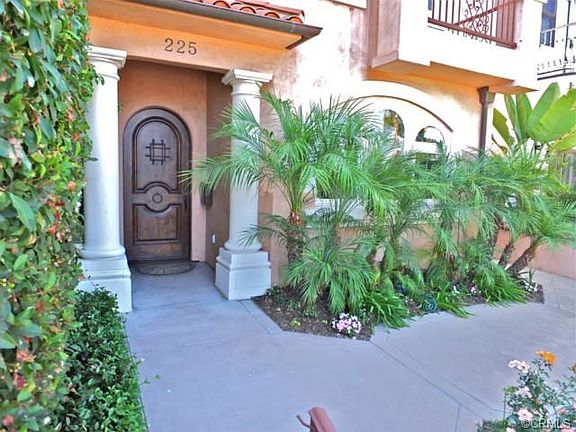 Custom dark wood arched doorway, paved walkway, and landscaping