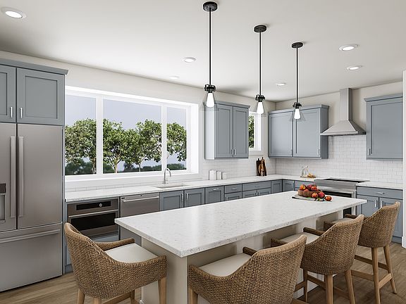 A modern, open-concept kitchen with gray cabinets, white countertops, and pendant lighting over a wo