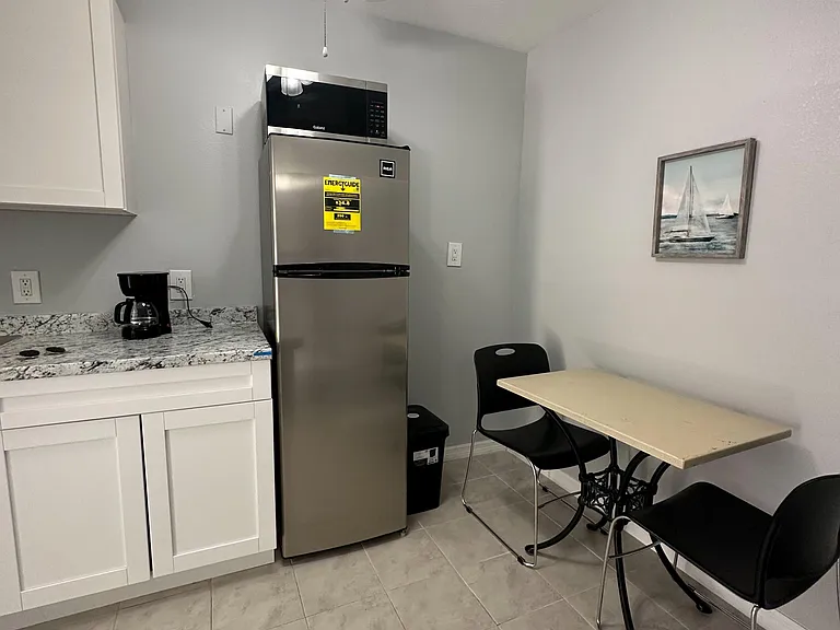 Efficient eat-in kitchen with ample cabinetry, granite-look counters, and a full-size fridge plus microwave for easy meals.