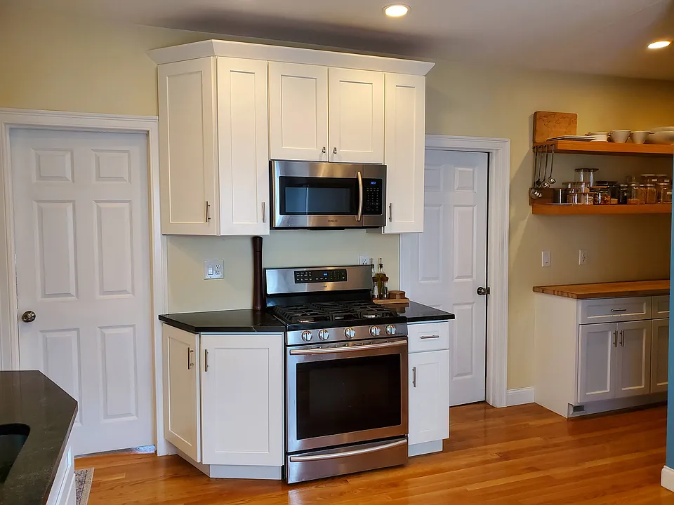 Kitchen area with dishwasher, french door refrigerator, stove/oven, and microwave. Bedroom 1 through the right door, Bedroom 2 through left door.