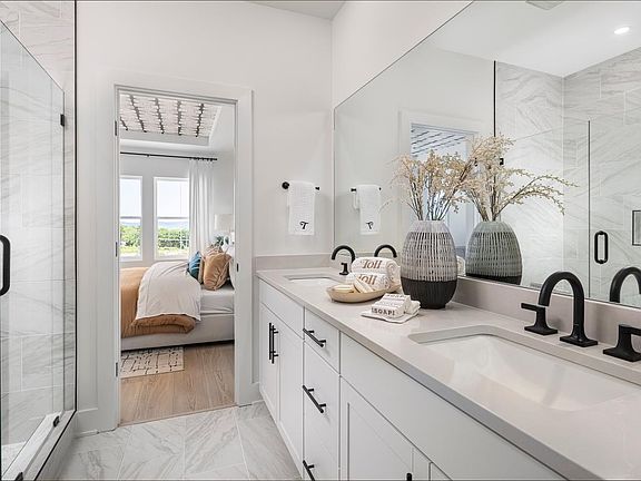 Spa-like primary bath boasts a dual-sink vanity and large glass shower
