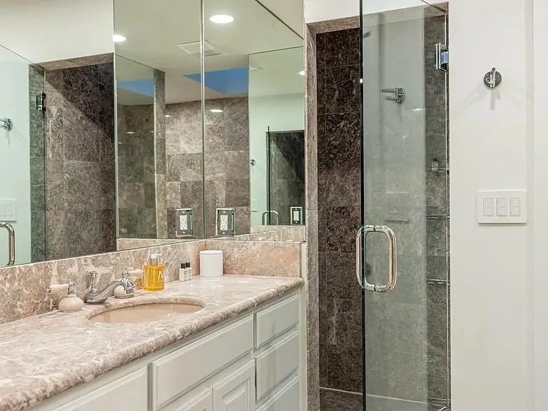 Step into luxury in the ensuite bathroom, featuring a walk-in glass shower and lavish toiletries.