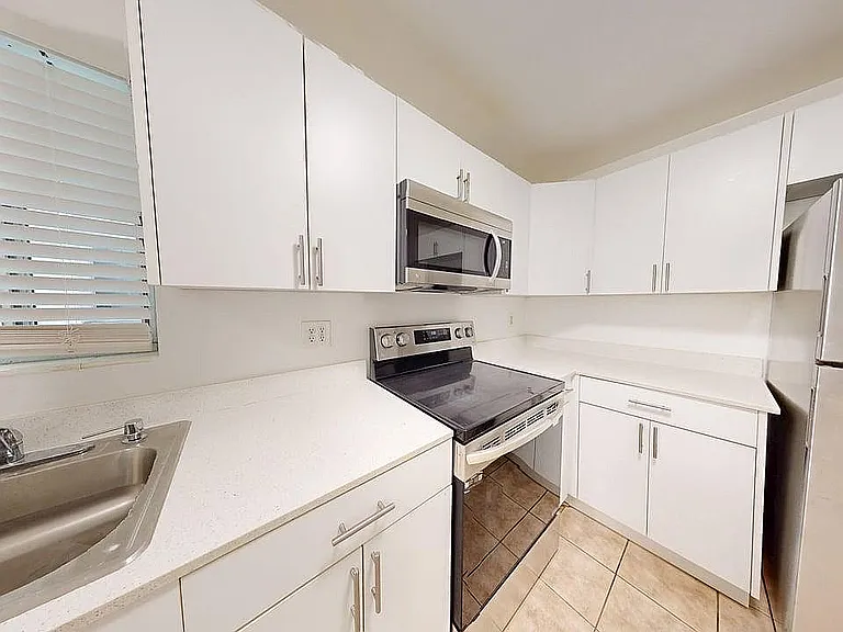 Modern kitchen with sleek white cabinetry, stainless steel appliances, and spacious countertops, offering a bright and inviting cooking space.