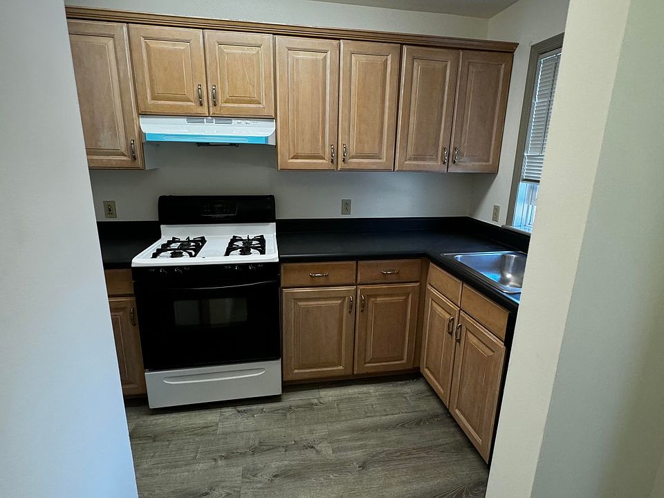 Kitchen area with grey vinyl flooring, oven/stove, refrigerator