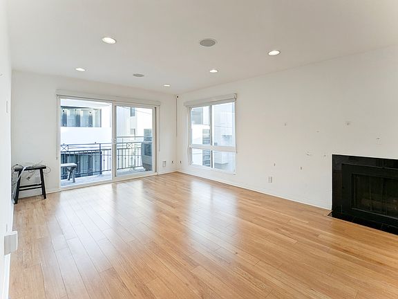 Living room with door to balcony and fireplace #1 inside of 28 Privateer St, unit 4, Marina del Rey, CA 90292 listed by listing agent, Eva Lee with Coldwell Banker Hallmark Realty.