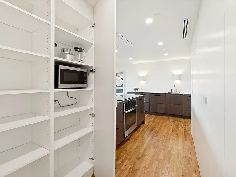 The shelved pantry is spacious and well-organized. The GE washer and dryer are behind the doors on the right in this picture.