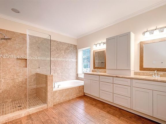 Updated luxurious master bath. Glass-surround walk in shower with rain head, jetted spa tub, dual porcelain sinks, granite counters, wood-grain tile floors, updated lighting and plumbing.