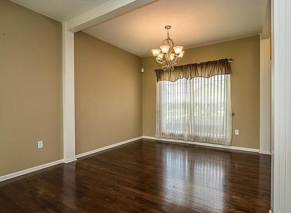Another view of the dining room with pretty chandolier and gleaming hardwood floors.