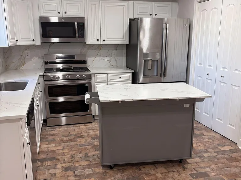 Well-equipped kitchen with stainless steel appliances, generous cabinet storage, and a movable prep island.
