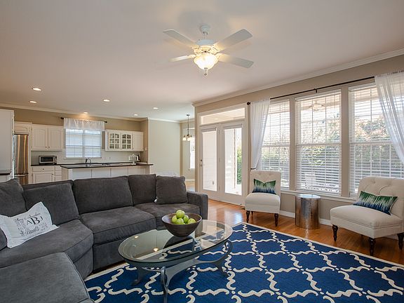 Wall of windows with privacy blinds overlooks covered patio and park-like backyard.