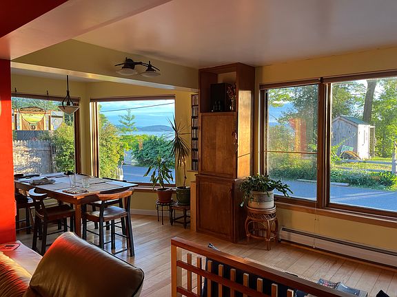 View of the dining area from the wood stove area in the living room with a lake view in the background
