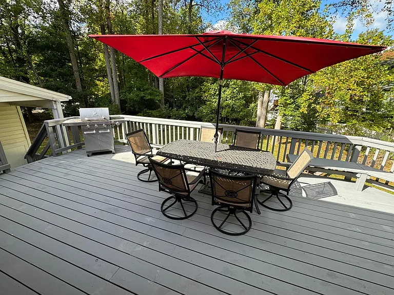 Freshly painted deck overlooking large back yard with mature trees.