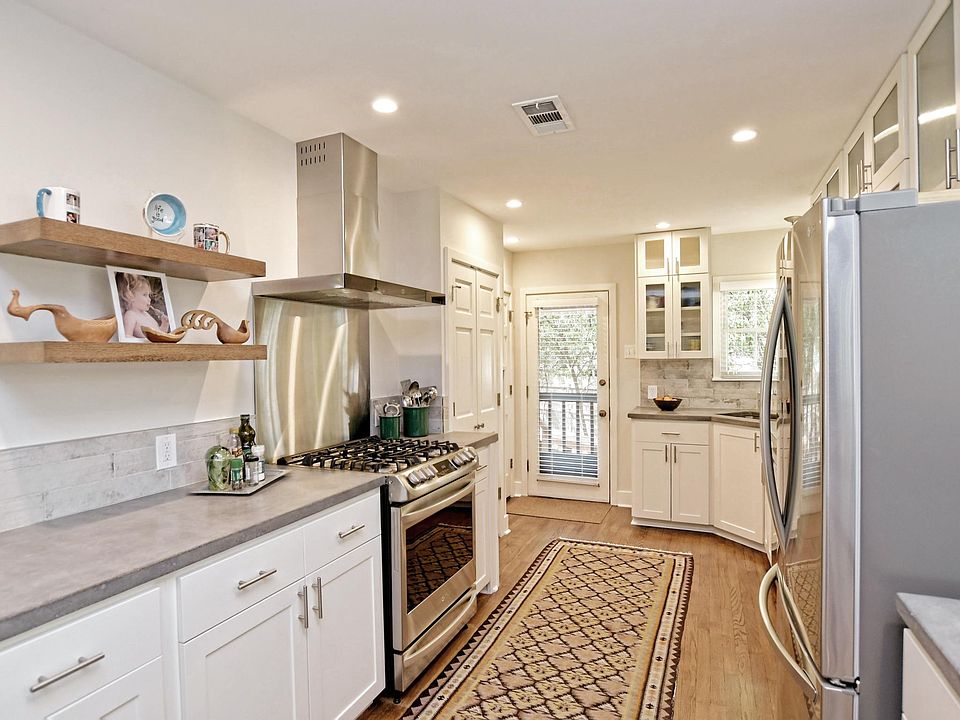 Recent kitchen with white cabinets, concrete counter tops, SS appliances including a gas range.