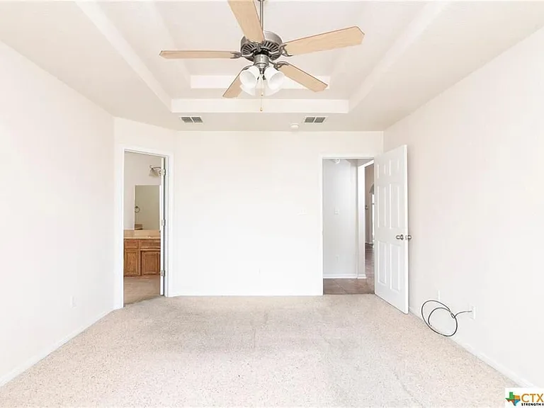 Large master bedroom with picture frame ceilings and ceiling fan.
