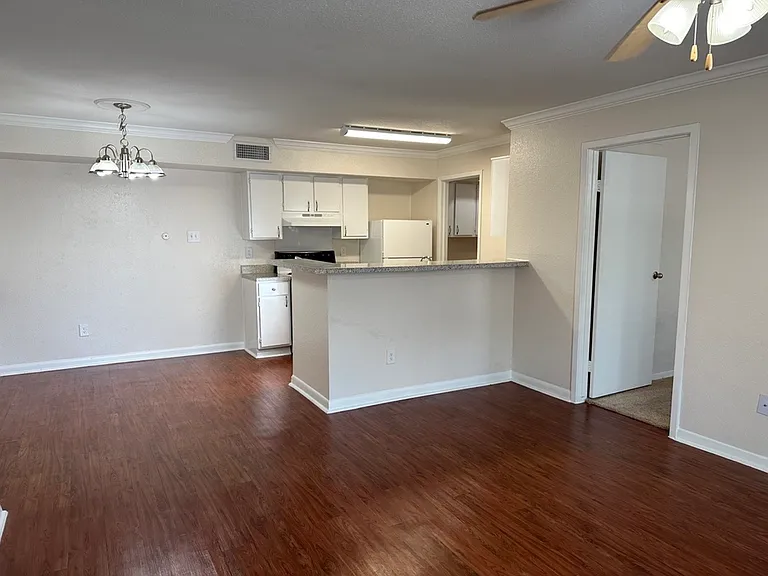 Inviting open-plan living area with elegant wood-style flooring, spacious kitchen, and modern lighting accents. Inviting open-plan living area with elegant wood-style flooring, spacious kitchen, and modern lighting accents.